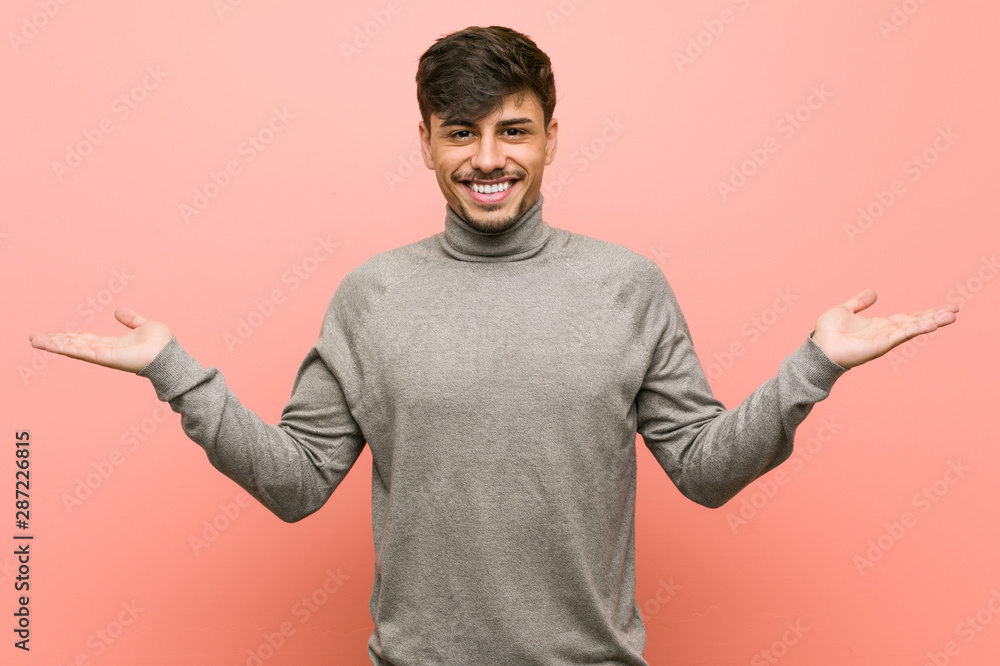 Young smart student man makes scale with arms, feels happy and confident. Young smart student man makes scale with arms, feels happy and confident.
