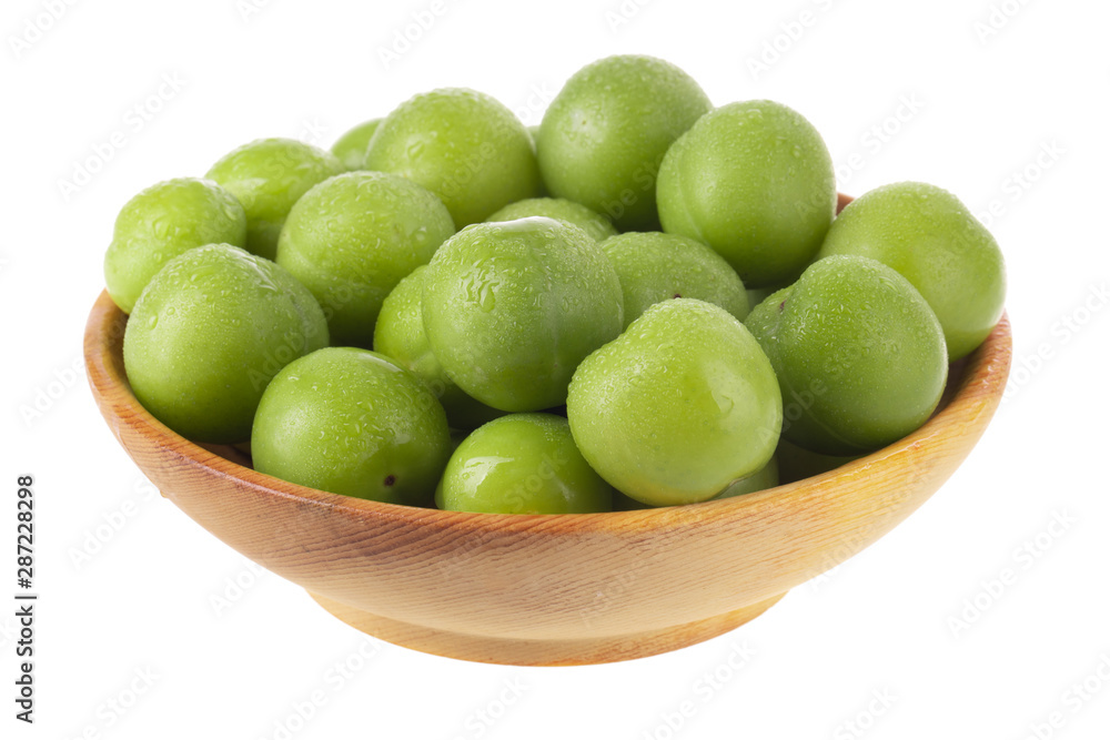 heap green cherry-plum in wooden plate isolated on white background heap green cherry-plum in wooden plate isolated on white background