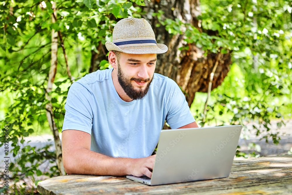 One young man uses a laptop outdoors. One young man uses a laptop outdoors.