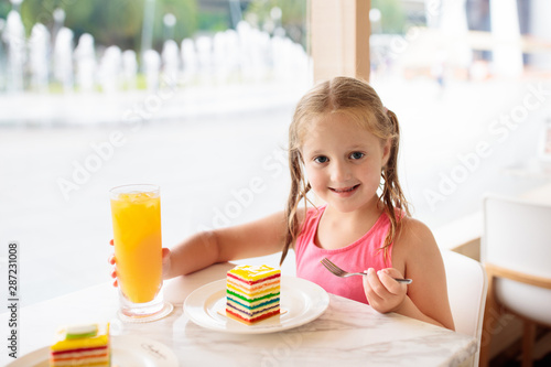 Kids eat cake at restaurant. Little girl in cafe.