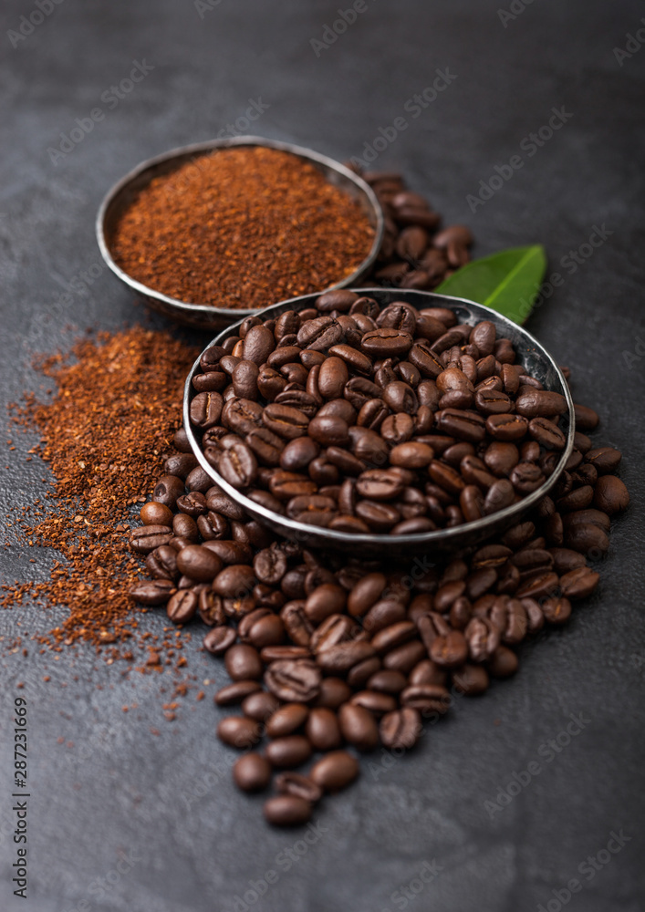 Fototapeta premium Fresh raw organic coffee beans with ground powder and coffee trea leaf on black background.