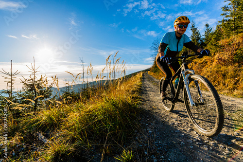 Fototapeta Naklejka Na Ścianę i Meble -  Cycling woman riding on bike in autumn mountains forest landscape. Woman cycling MTB flow trail track. Outdoor sport activity.