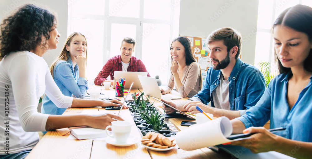 Group of young modern team in smart casual wear are discussing something while working in the creative office. Start up. Coworking space. Business ideas