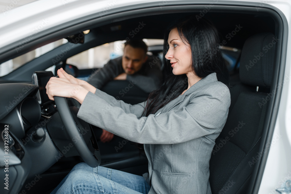 Cheerful couple buying new car in showroom Cheerful couple buying new car in showroom