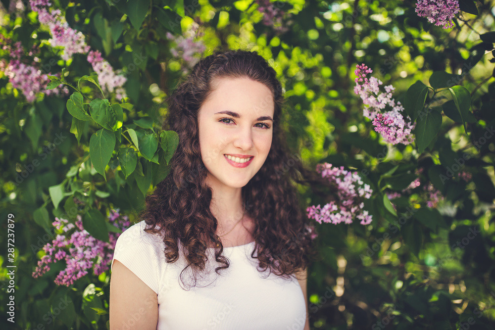 Cheerful young woman in a white t-shirt under the blooming trees. Cheerful young woman in a white t-shirt under the blooming trees.