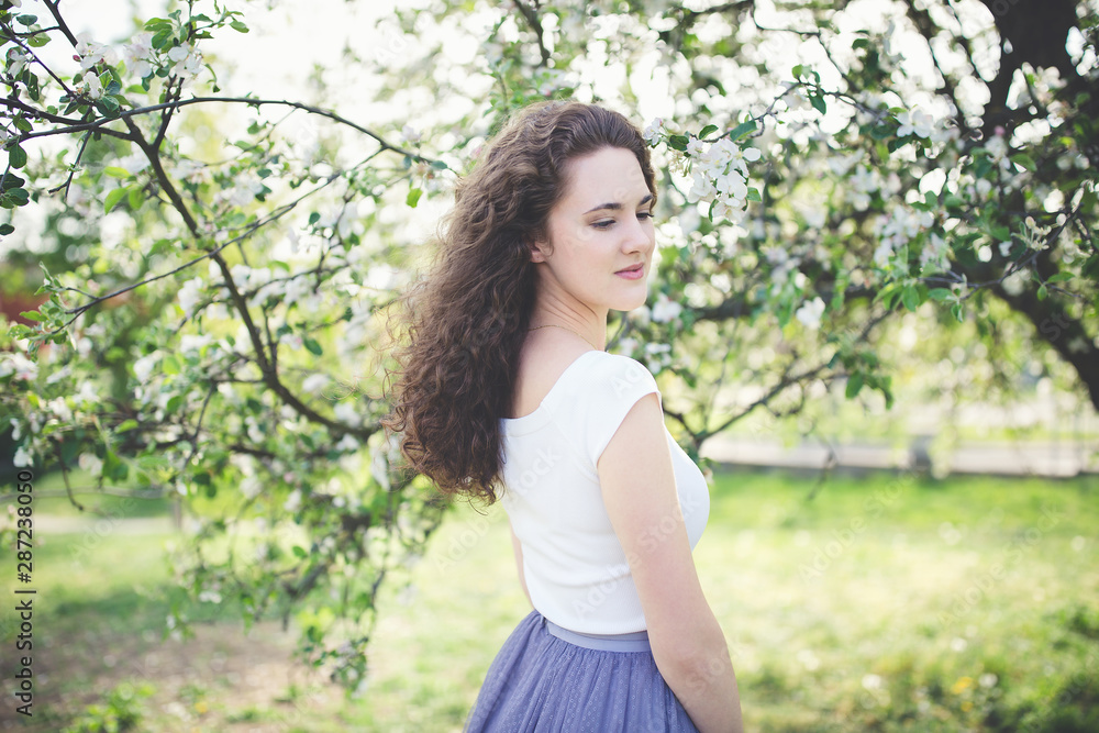 Cheerful young woman in a white t-shirt under the blooming tree. Cheerful young woman in a white t-shirt under the blooming tree.