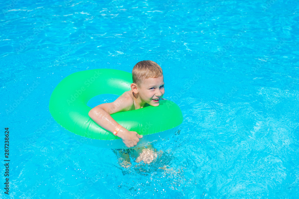 Happy kid boy having fun in an swimming pool. Active happy healthy preschool child learning to swim. With safe floaties or swimmies.