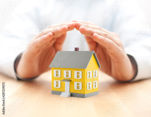 Small yellow house covered by hands 