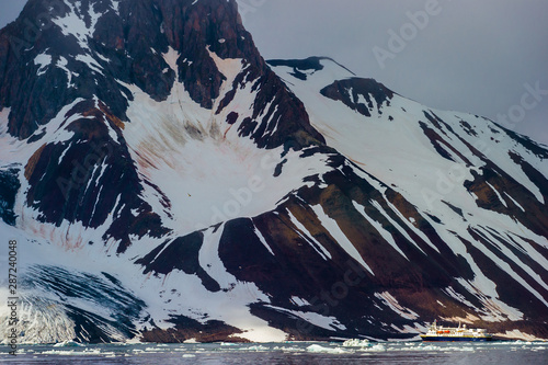 HORNSUND, SVALBARD, NORWAY – JULY 26, 2010:  National Geographic Explorer cruise ship in front of a glacier in the Arctic Ocean. photo