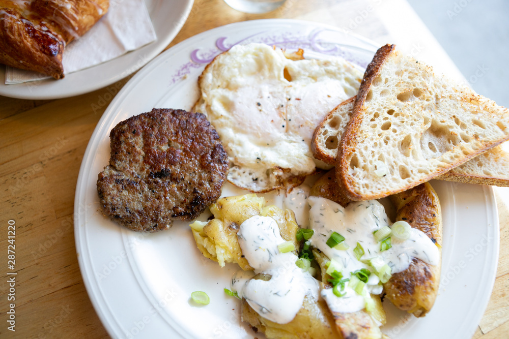 American breakfast with sausage patty, sourdough bread toast, fried egg, and potatoes, top view American breakfast with sausage patty, sourdough bread toast, fried egg, and potatoes, top view