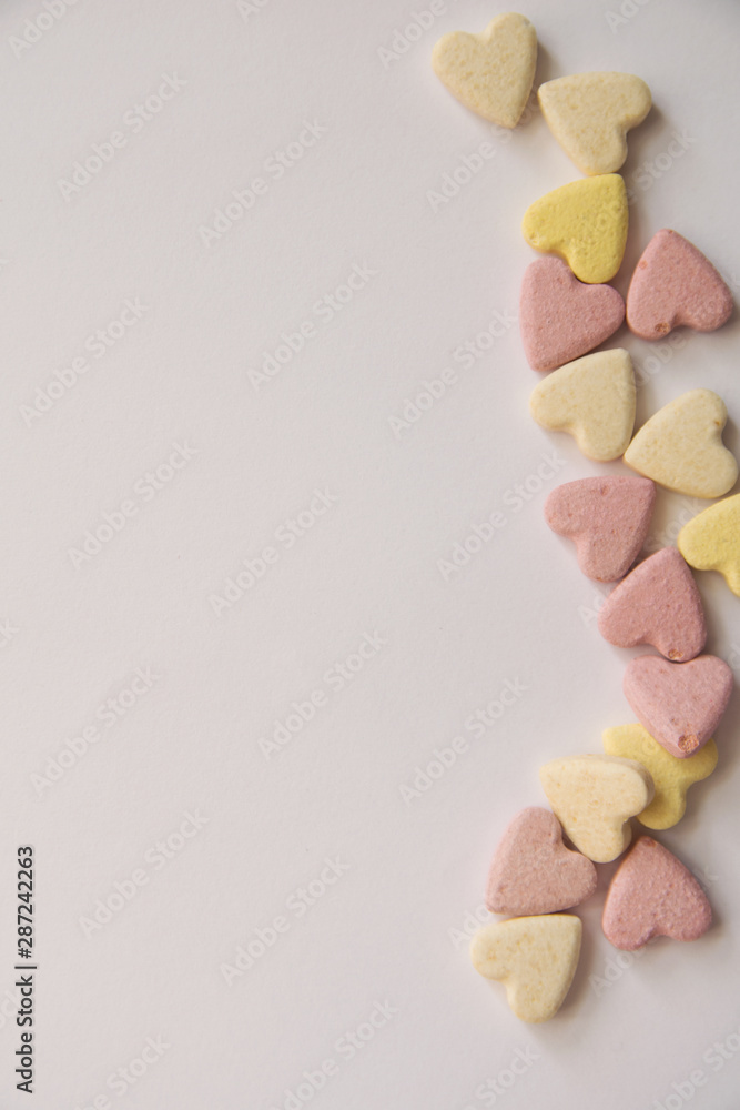 pink and yellow Vitamins in the shape of a heart lie on a white background in equal order on one side of the sheet leaving an empty spot pink and yellow Vitamins in the shape of a heart lie on a white background in equal order on one side of the sheet leaving an empty spot