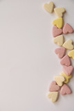 pink and yellow Vitamins in the shape of a heart lie on a white background in equal order on one side of the sheet leaving an empty spot