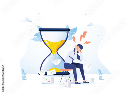Tired and exasperated office worker is sitting near hourglass and grabbed his head with business papers
