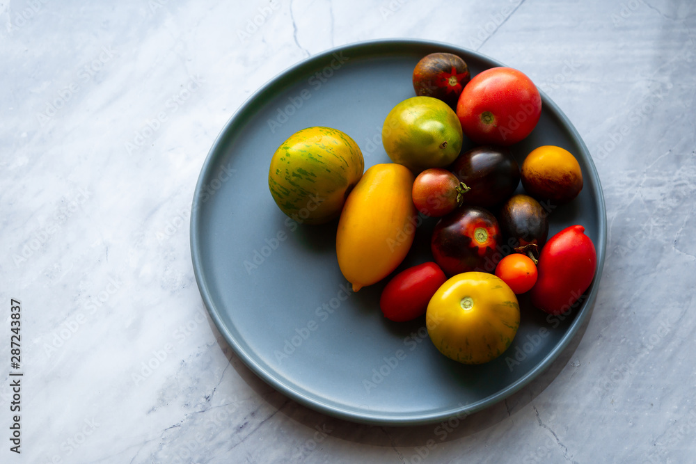 Tomatoes of different varieties in a bowl. Multi-colored washed crop on a plate. Cherry collected from the garden Tomatoes of different varieties in a bowl. Multi-colored washed crop on a plate. Cherry collected from the garden