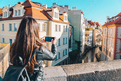 woman taking picture of river canal between buildings on her phone