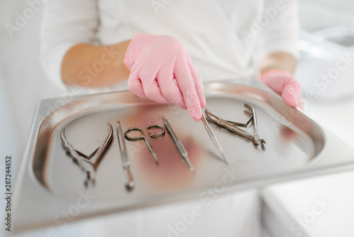 Cosmetologist holds metal tray with equipment