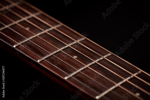 Guitar fretboard close-up. Black background. 
