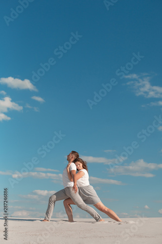 Romantic couple dancing in sand desert at blue sky background