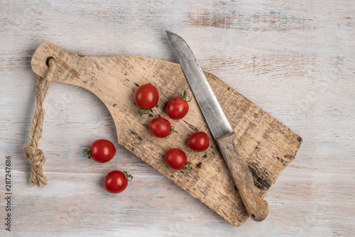 ripe cherry tomatoes and knife on a wooden table