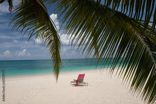 A lone beach lounge sits on a empty tropical beach