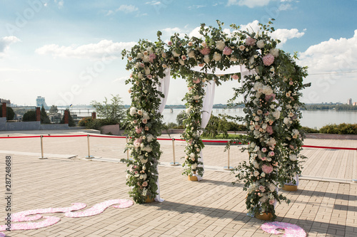 A festive chuppah decorated with fresh beautiful flowers for an outdoor wedding ceremony photo