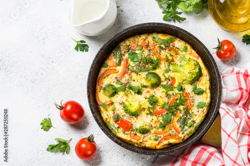 Frittata with vegetables on white stone table.