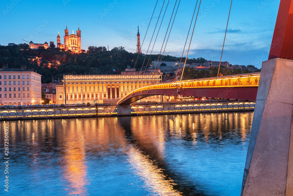 Lyon night cityscape with illuminated Courthouse and red pedestrian bridge over Saone river. Panoramic blue hour landscape