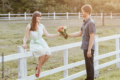 The guy theatrically gives a bouquet to his bride. Etude love in the park. Newlyweds on a sunny day with a bouquet photo