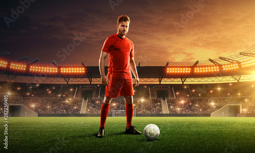 Soccer player in sport uniform ready for the game. Stadium with green grass, tribunes and dramatic night sky