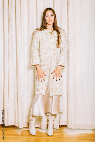 Fashion portrait of beautiful young woman wearing tweed long jacket and silk skirt