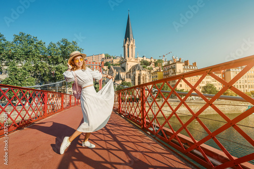 Happy Asian girl traveler and tourist walks through the center of Lyon's old town and enjoys the view of Eglise Saint Georges Church on the banks of the Saone river