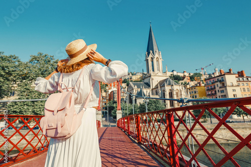 Happy Asian girl traveler and tourist walks through the center of Lyon's old town and enjoys the view of Eglise Saint Georges Church on the banks of the Saone river