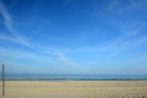 Empty sand beach and ocean with bright blue sky on a sunny summer day on island Texel in North Netherlands