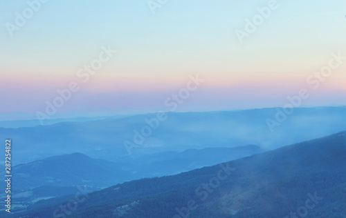 Mountain range with visible silhouettes through the evening fog.