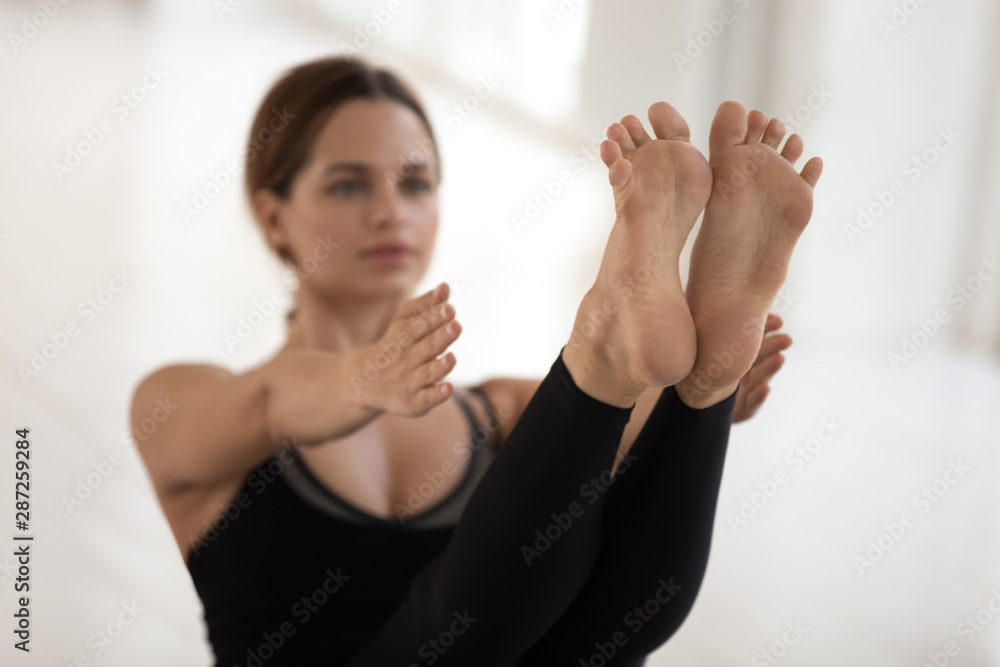 Woman doing Paripurna Navasana exercise, practicing yoga, feet close up  Stock Photo