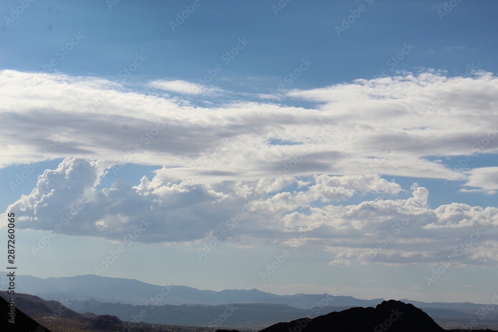 Assemblages of vapor waft above Southern Mojave Desert land surrounding the West Entrance to the environment of Joshua Tree National Park, with the town of Joshua Tree visible several miles behind.