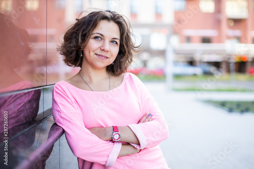 Fotografija Young Caucasian woman with crossed arms and slight smile leaned against the wall
