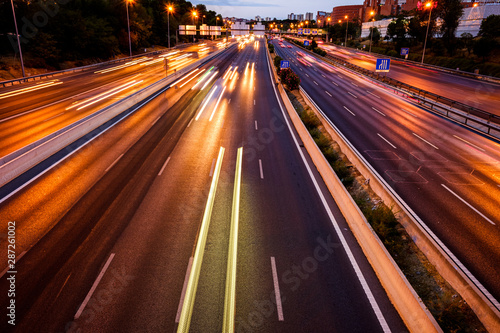 Trails of car lights on a large road at night.