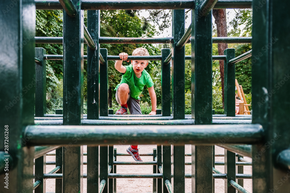 Obraz premium Boy playing in a maze of wooden bars in a park.