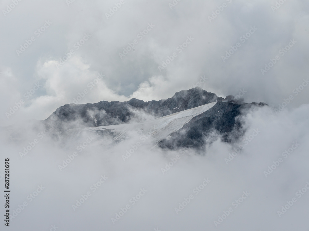 Mysterious mountain Peak seen through waves of fog and cloud