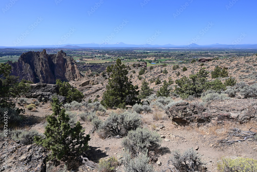 View of Terrebonne and distant volcanoes from Misery Ridge Trail in Smith Rock State Park, Oregon on a clear cloudless summer day.