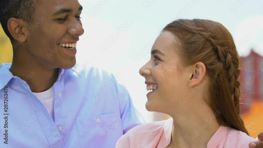 Playful male teen walking to girlfriend, closing eyes with palms, romantic date Playful male teen walking to girlfriend, closing eyes with palms, romantic date