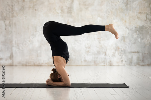 Woman practicing yoga, headstand, variation of salamba sirsasana exercise