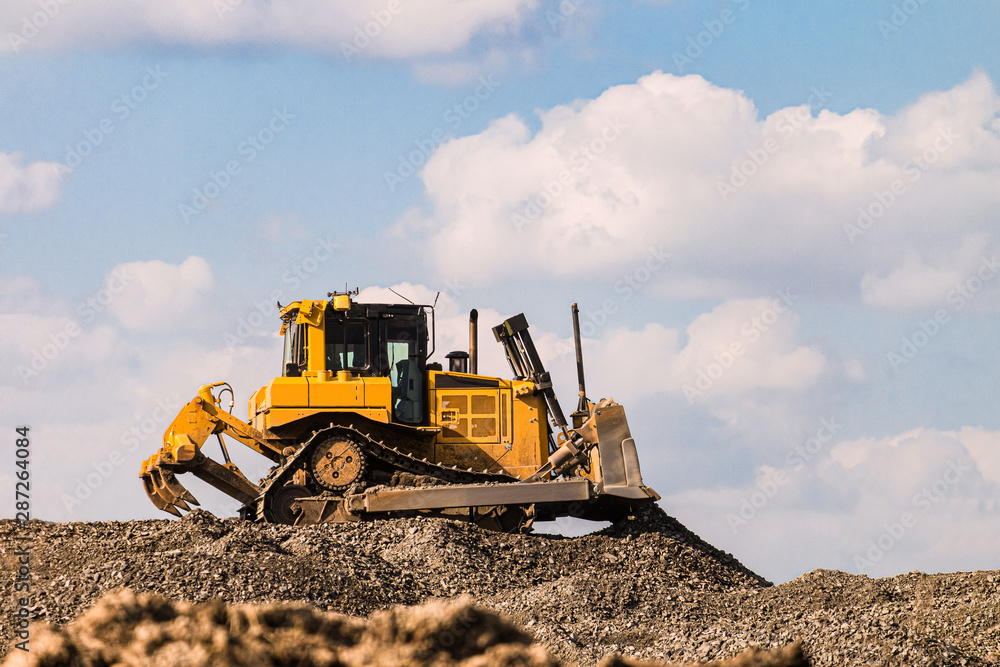 Yellow motorized bulldozer raking rubble piles. Road building industry. Yellow motorized bulldozer raking rubble piles. Road building industry.