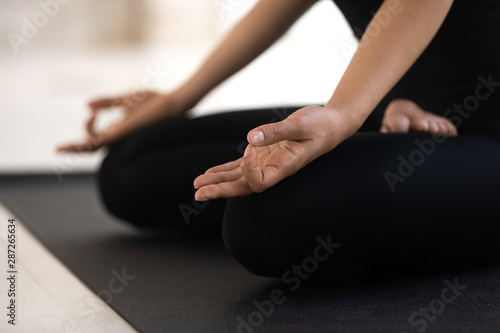 Woman sitting in lotus pose close up, practicing yoga, Padmasana exercise