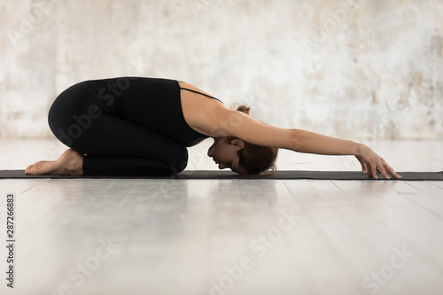Beautiful woman practicing yoga, relaxing in Child pose, Balasana exercise