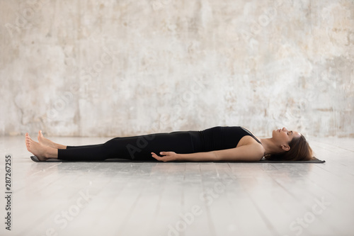Young woman practicing yoga, Savasana, Dead Body pose, Corpse photo
