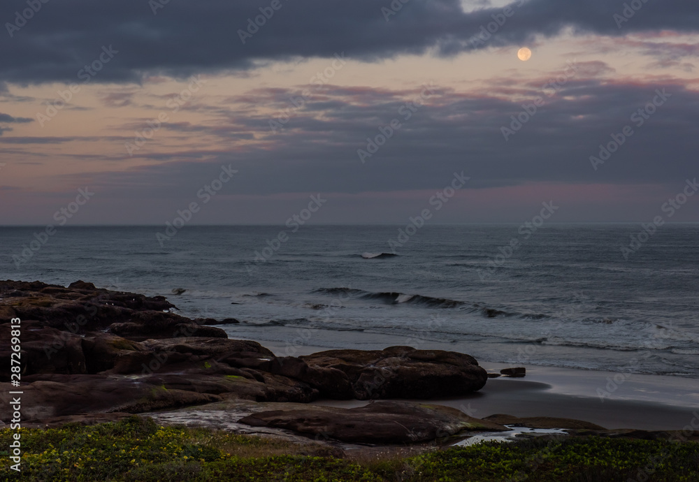 Pacific Ocean seascape with the full moon setting at sunrise, Yachats Oregon