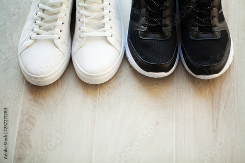Pair of new stylish white sneakers on wood floor.