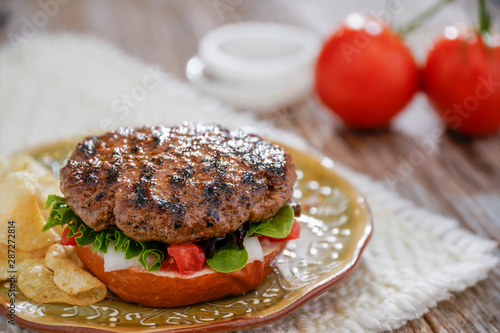 Homemade hamburger on plate with fixins. Delicious sandwich hamburger with meat or pork ham cheese and fresh vegetable. Hamburger or sandwich is the popular fast food for brunch or lunch. photo